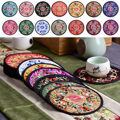 Nuancier des quatorze coloris disponibles au-dessus d'une pile de dessous de verre brodés posée à côté d'une tasse.