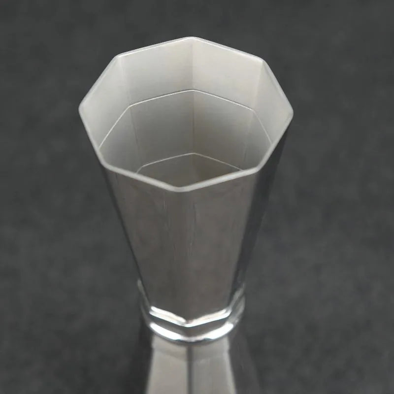 Vue macro plongeante sur l'ouverture octogonale du grand godet du doseur à cocktail en inox.