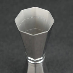 Vue macro plongeante sur l'ouverture octogonale du grand godet du doseur à cocktail en inox.