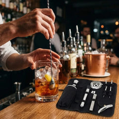 Barman préparant un cocktail à la cuillère de mélange torsadée, avec la trousse d'accessoires posée sur le comptoir