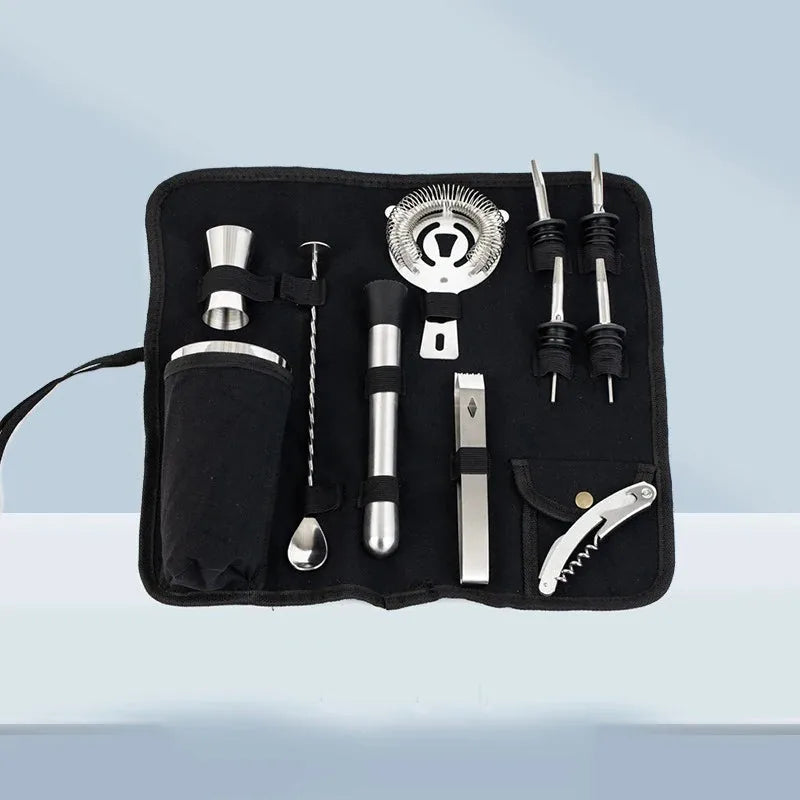 Vue d'ensemble du kit cocktail avec sa pochette en tissu noire déroulée, sur fond dégradé gris bleuté