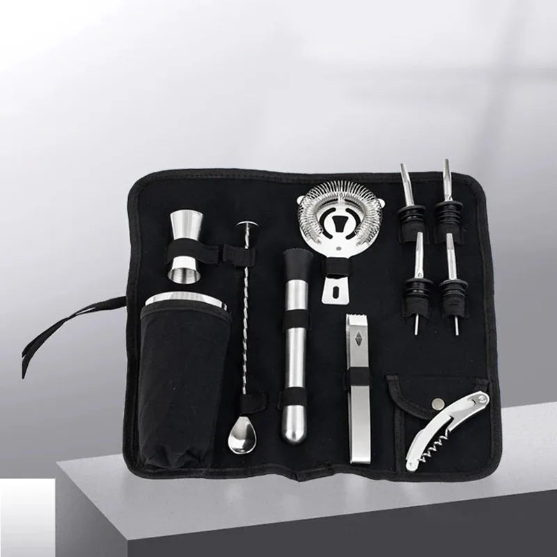 Trousse de bar en toile noire ouverte en perspective, laissant apparaître le shaker, la passoire et les doseurs