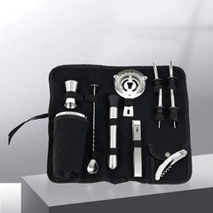 Trousse de bar en toile noire ouverte en perspective, laissant apparaître le shaker, la passoire et les doseurs
