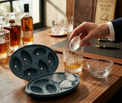 Glaçon en forme de ballon de rugby déposé dans un verre de whisky sur un bureau élégant