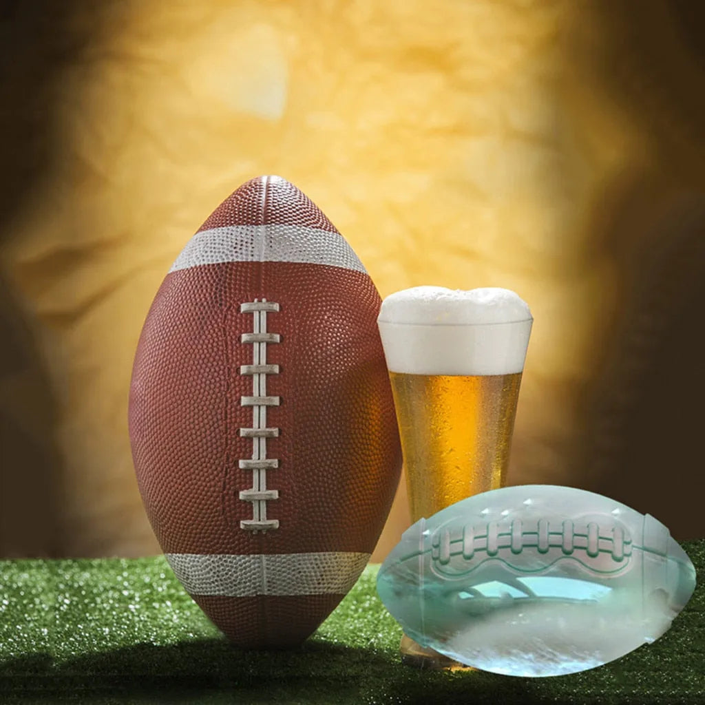 Glaçon transparent en forme de ballon de rugby posé à côté d'un vrai ballon et d'une bière sur un terrain