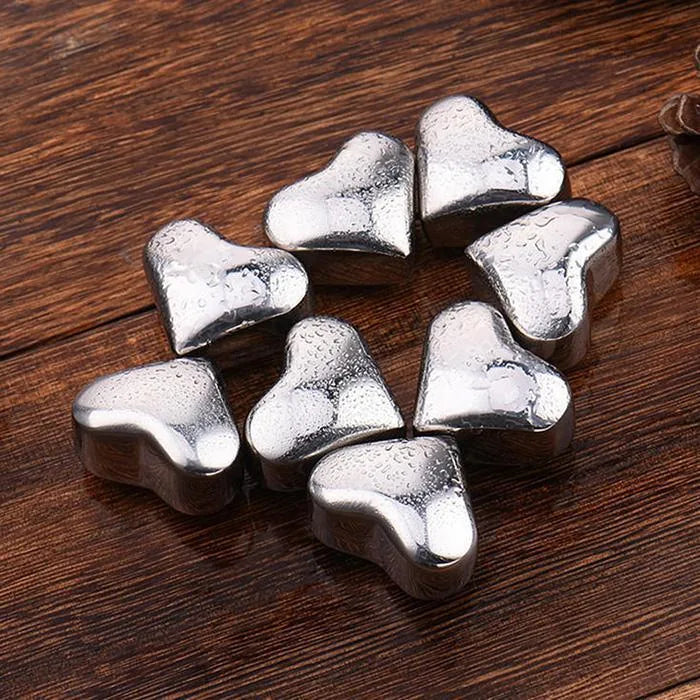 Huit glaçons en forme de cœur disposés en cercle sur du bois, recouverts de fines gouttes d'eau.