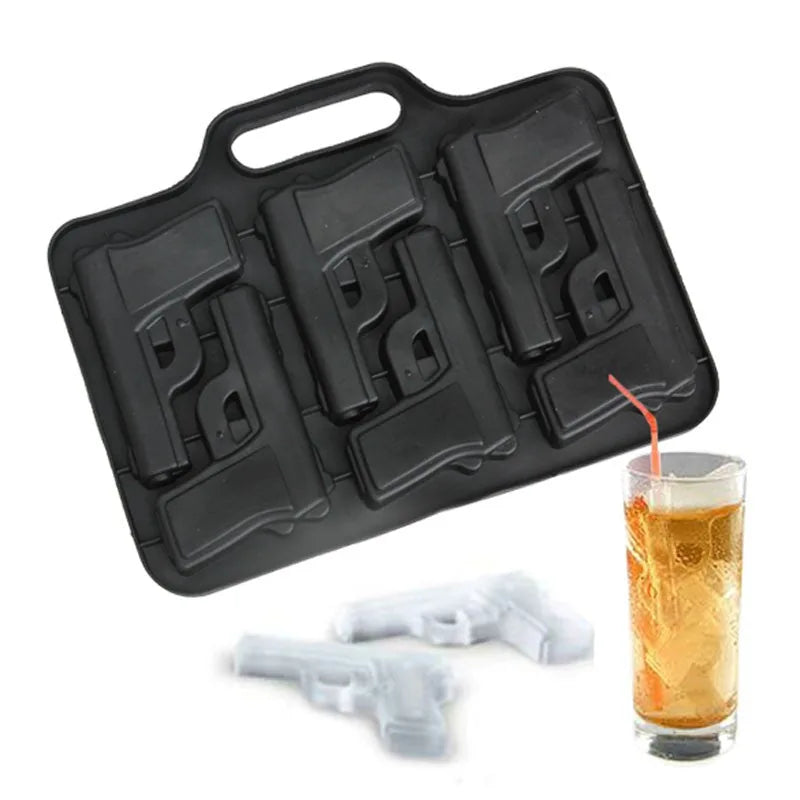 Moule à glaçons pistolet avec un glaçon démoulé posé devant, à côté d'un verre de cocktail rempli de glaçons en forme de pistolet et d'une paille rouge