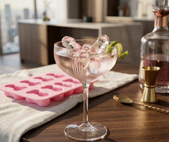 Glaçons en forme de zizi dans une coupe de cocktail avec un zeste de citron vert, ambiance appartement avec vue sur la ville