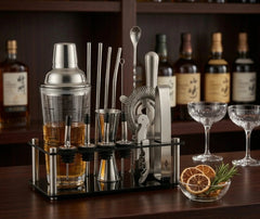 Kit cocktail avec shaker posé sur un bar en bois, entouré de bouteilles, verres et agrumes séchés