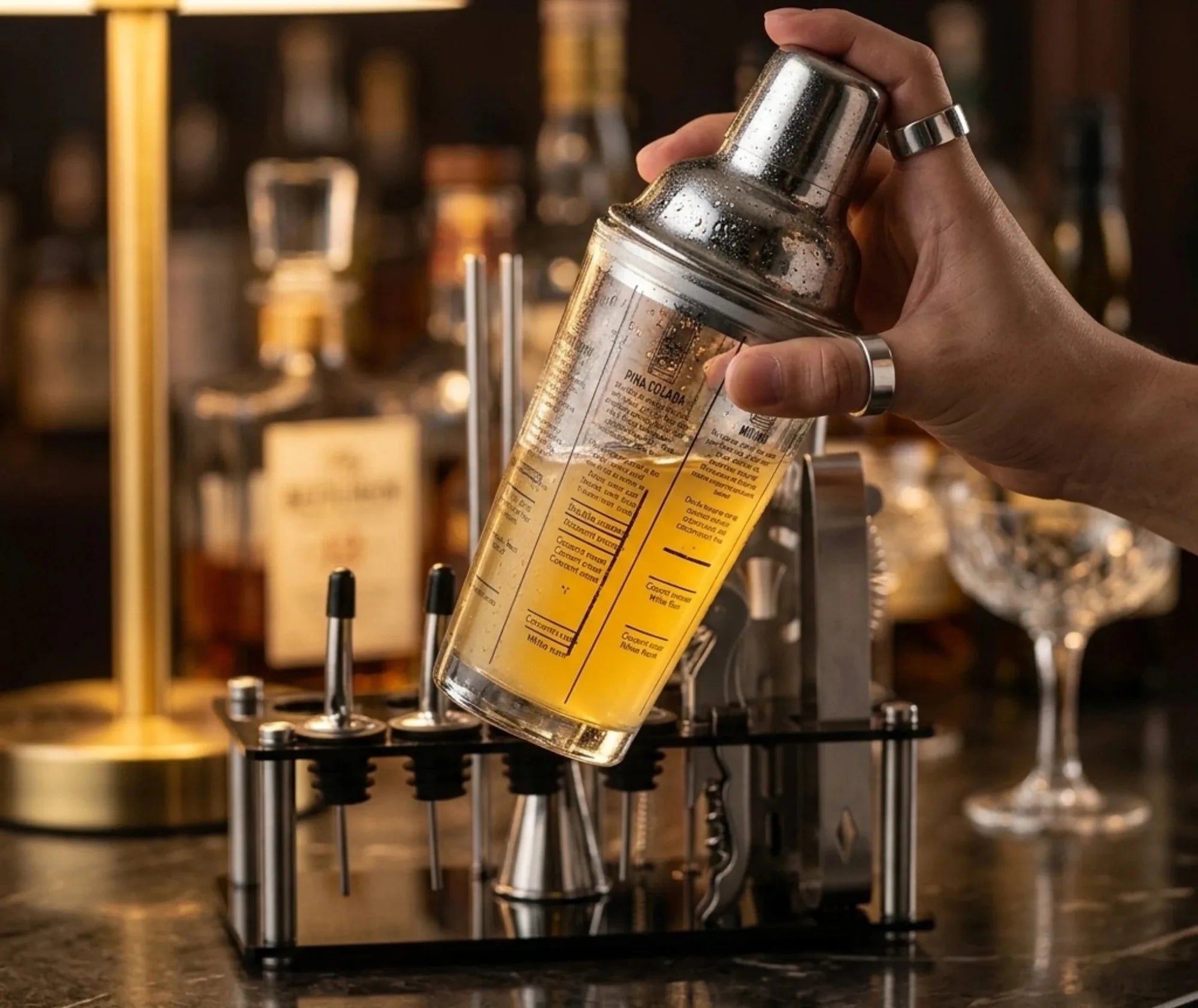 Main tenant le shaker du kit cocktail au-dessus du bar, cocktail Piña Colada en préparation
