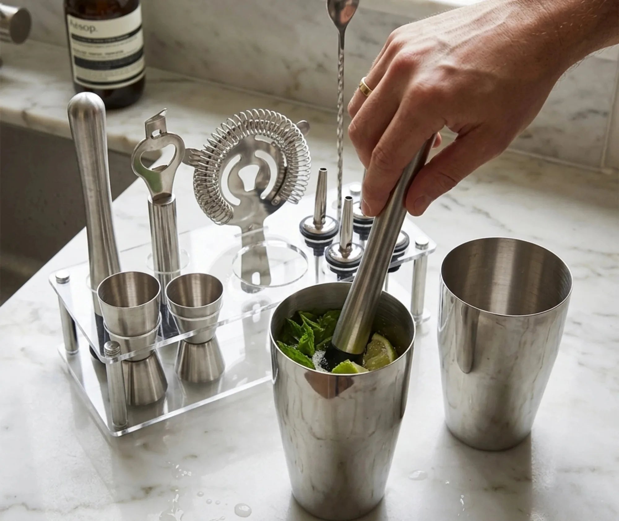 Préparation d'un cocktail à la menthe et au citron vert avec le kit cocktail DIY sur un plan de travail en marbre