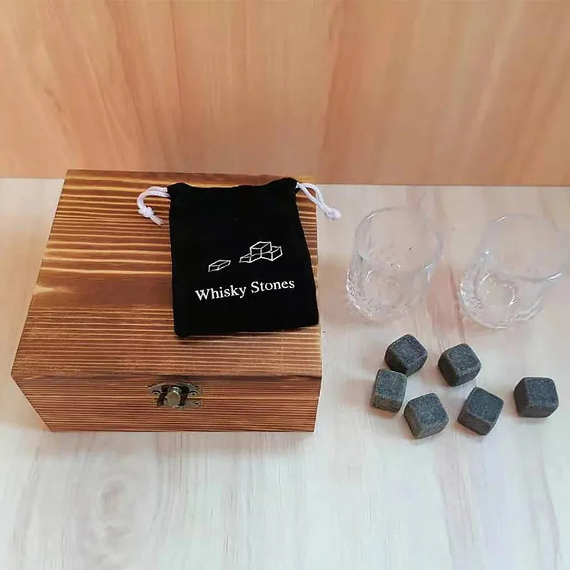 Coffret en bois fermé du kit de verres à whisky, accompagné de la pochette Whisky Stones, des 2 verres en cristal et des 6 pierres disposées à côté