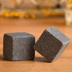 Gros plan macro sur deux pierres à whisky en granit gris posées sur une table en bois