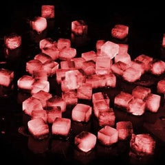 Gros plan sur de nombreux petits glaçons translucides éclairés en rouge, dans une ambiance sombre et festive.