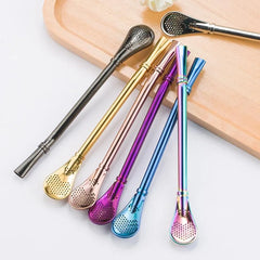 Six pailles à mojito en métal de couleurs variées posées sur une planche en bois, avec un gros plan sur un embout filtrant argenté.