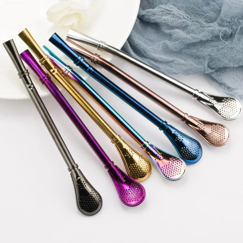 Collection de huit pailles à mojito en métal de couleurs différentes disposées en éventail sur une assiette blanche.