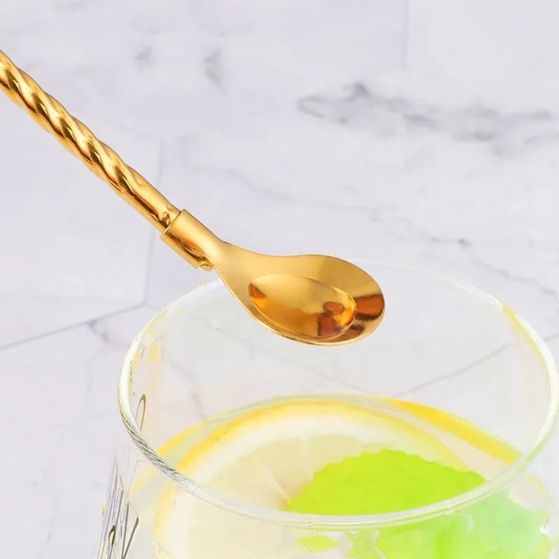 Gros plan sur une paille cuillère dorée plongée dans un verre garni d'une rondelle de citron