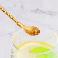 Gros plan sur une paille cuillère dorée plongée dans un verre garni d'une rondelle de citron