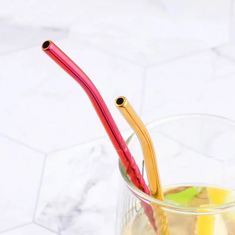 Gros plan sur deux pailles cuillères rouge et doré dépassant d'un verre de cocktail