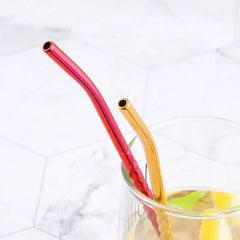 Gros plan sur deux pailles cuillères rouge et doré dépassant d'un verre de cocktail