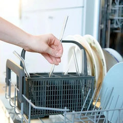 Une main place une paille en verre dans le panier à couverts d'un lave-vaisselle pour illustrer son entretien facile.