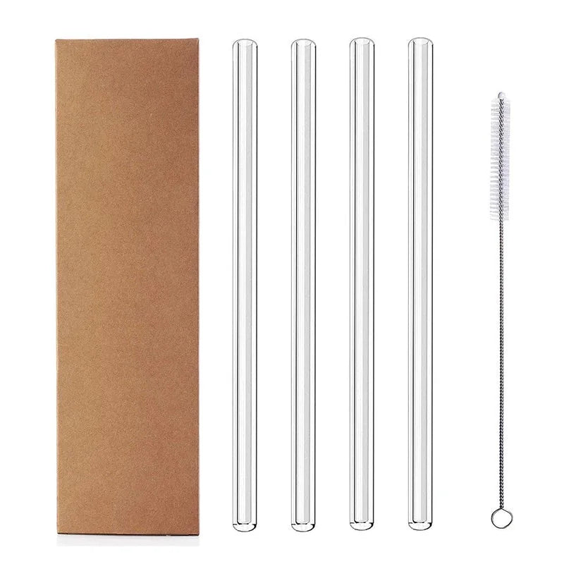 Quatre pailles en verre droites alignées à côté d'un goupillon de nettoyage et de leur boîte kraft.