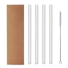 Quatre pailles en verre droites alignées à côté d'un goupillon de nettoyage et de leur boîte kraft.