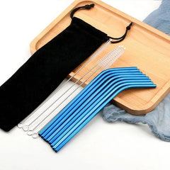 Pailles cocktail bleues courbées disposées sur un plateau en bois avec pochette noire et brosses de nettoyage.