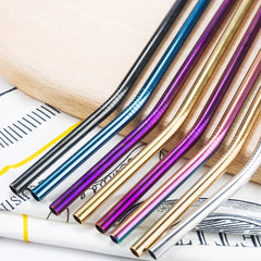 Gros plan macro sur les embouts de pailles cocktail de couleurs variées (argent, noir, bleu, violet, doré, rose) posées sur un tissu.