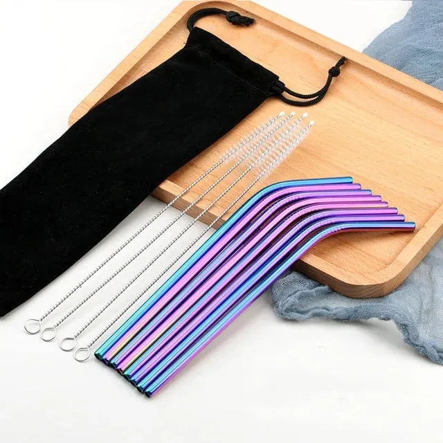 Pailles cocktail multicolores irisées courbées disposées sur un plateau en bois avec pochette et brosses de nettoyage.