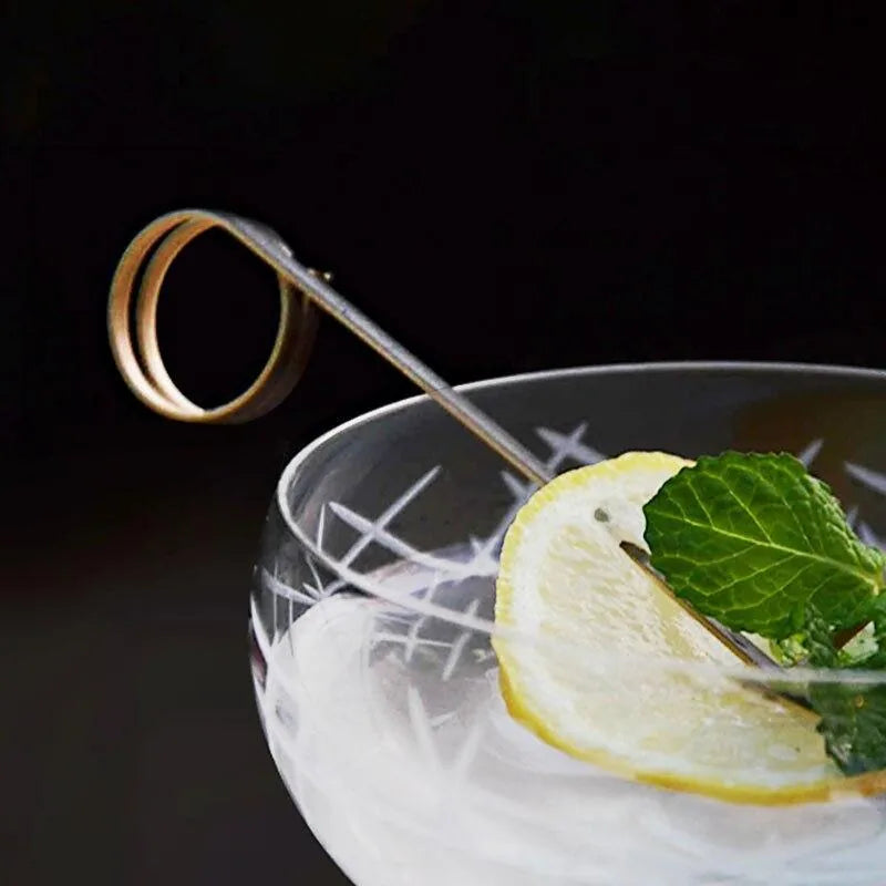 Pique à cocktail noir élégance avec une rondelle de citron et une feuille de menthe sur un cocktail glacé.