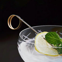 Pique à cocktail noir élégance avec une rondelle de citron et une feuille de menthe sur un cocktail glacé.