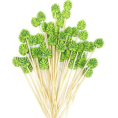 Bouquet d'une cinquantaine de piques à cocktail à motif feuille verte, présentés en éventail sur fond blanc.
