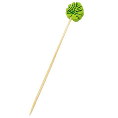 Pique à cocktail en bambou surmonté d'une feuille tropicale verte peinte à la main, vue détaillée sur fond blanc.