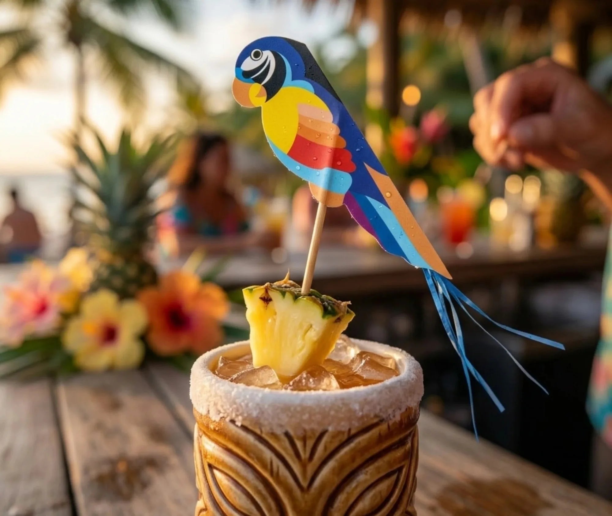 Pic à cocktail perroquet tropical planté dans un morceau d'ananas, décor plage au coucher du soleil