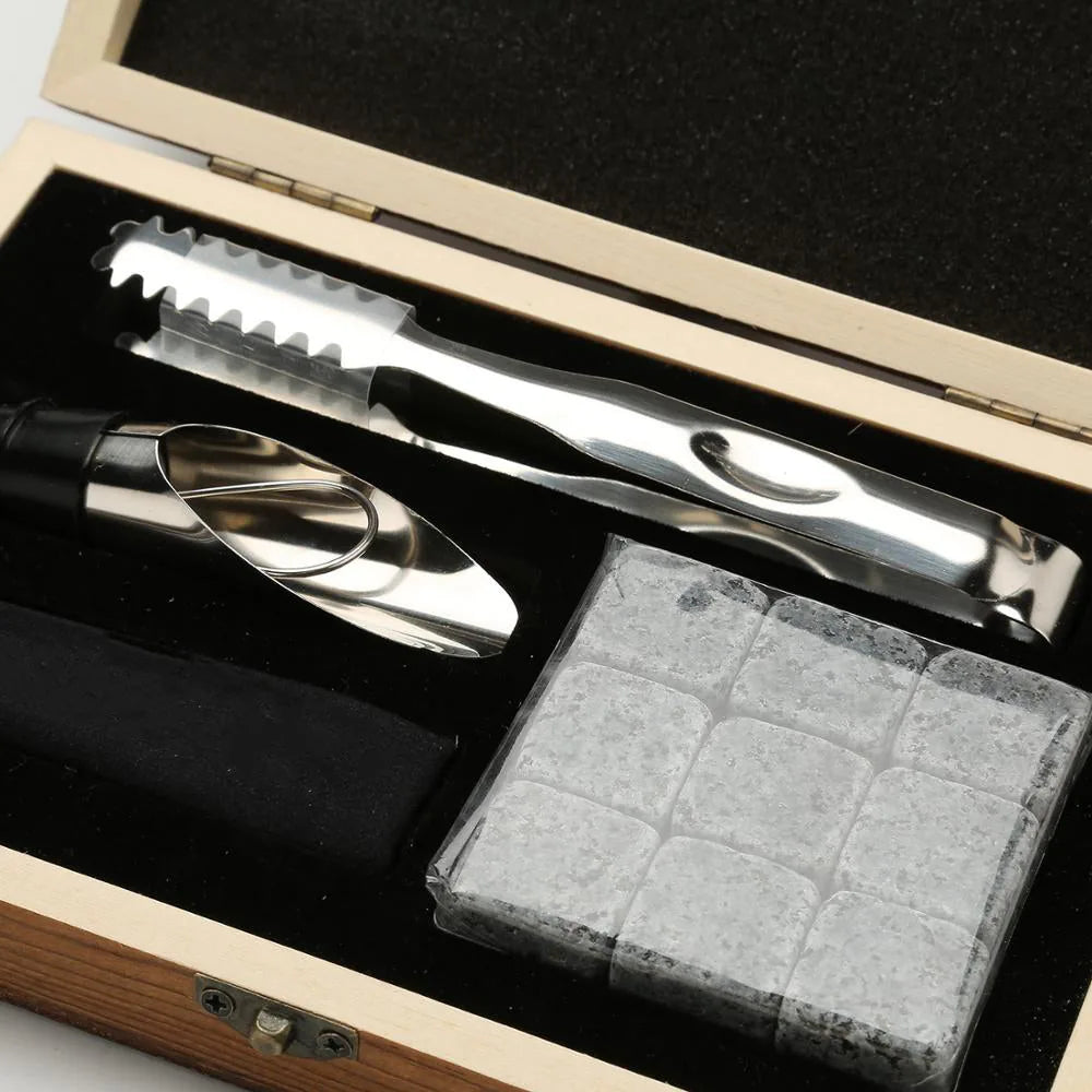 Gros plan sur les accessoires du coffret : pince de service, verseur et pierres à whisky emballées