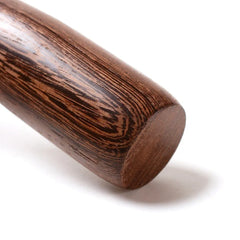 Gros plan macro sur l'embout arrondi du pilon en bois, mettant en valeur le veinage du bois