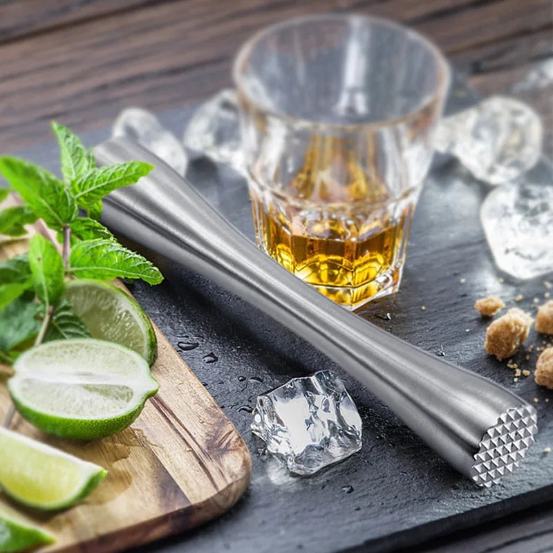 Le pilon posé sur une ardoise noire à côté d'un verre de whisky glacé, de menthe fraîche, de citron vert et de sucre roux.