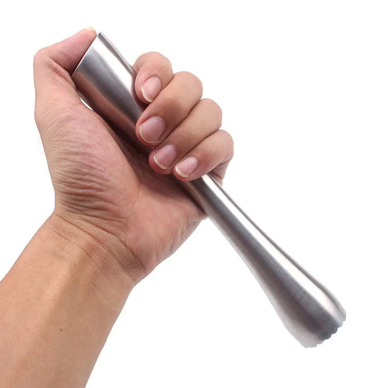 Une main tient fermement le pilon à cocktail en inox sur fond blanc, montrant sa prise en main.