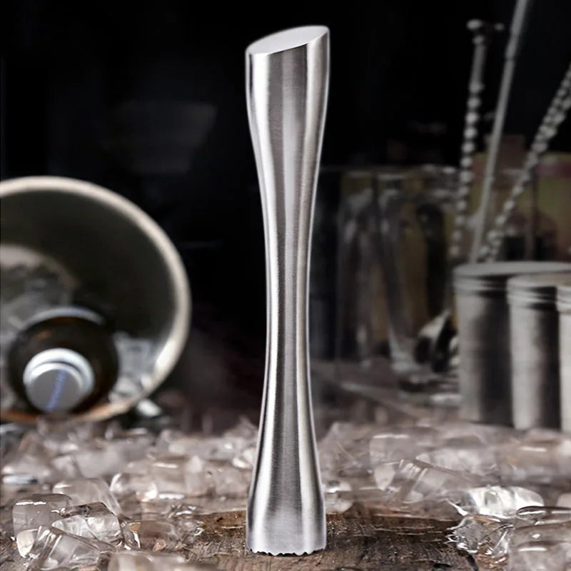 Le pilon planté verticalement dans de la glace pilée, avec un bar sombre flou en arrière-plan.
