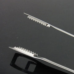 Gros plan sur les mors dentelés en inox de la pince à glace, conçus pour une prise ferme sur les glaçons, fond noir.