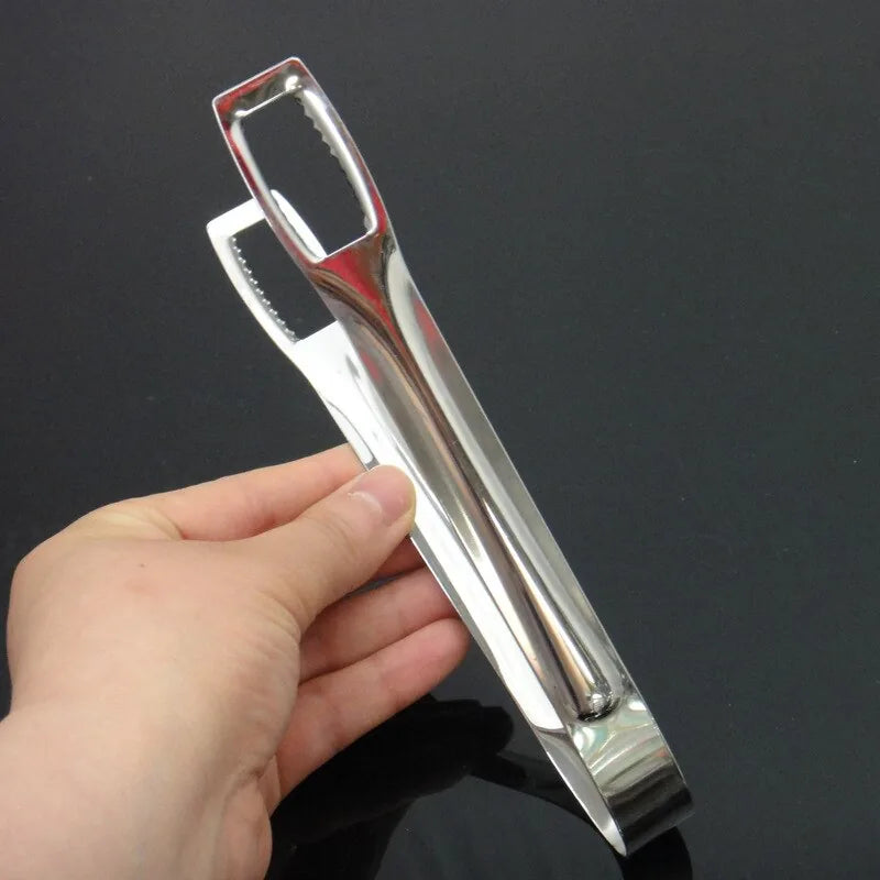Pince à glace en inox tenue en main, vue de profil complète montrant sa longueur et son design élégant, fond noir.