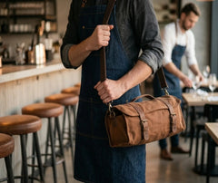 Barman en tablier en jean portant le sac de transport de Barman en bandoulière dans un restaurant