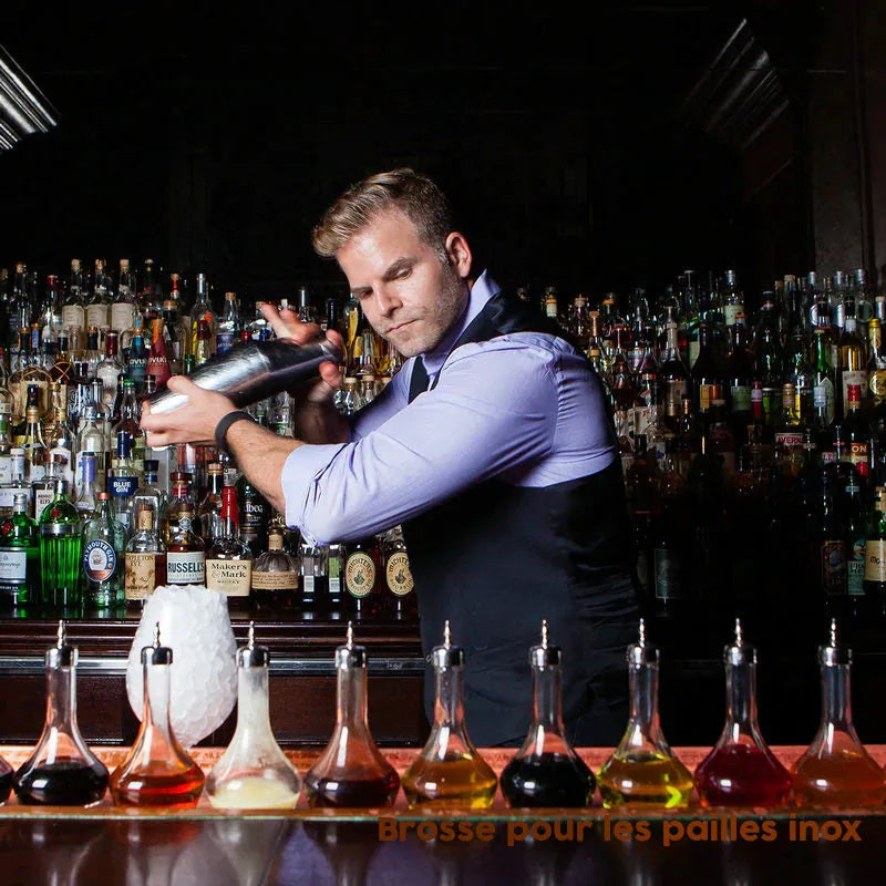 Barman professionnel secouant un shaker Boston devant un bar garni de bouteilles et de doseurs