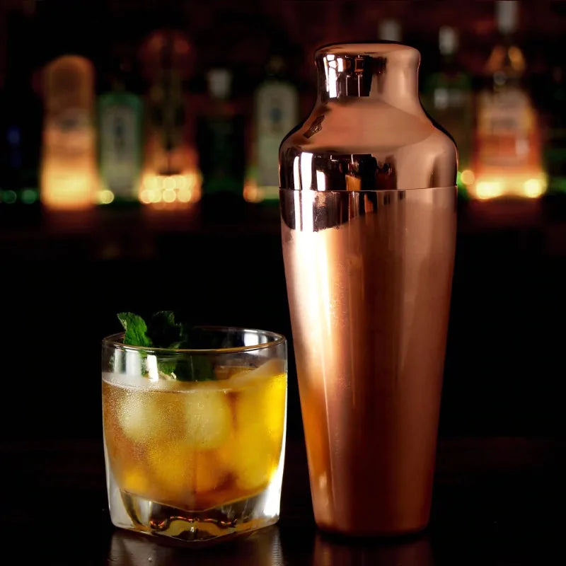 Shaker cocktail bar en cuivre posé sur un comptoir de bar à côté d'un cocktail glacé