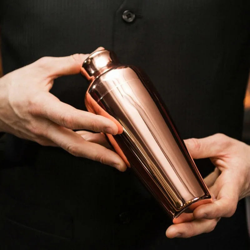 Shaker cocktail bar en cuivre tenu à deux mains par un barman en costume