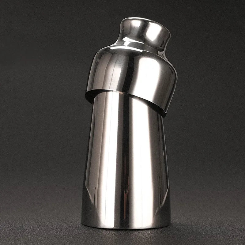 Shaker à cocktail en inox argenté, vue inclinée sur fond sombre dégradé.