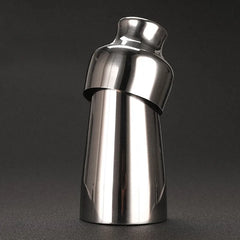 Shaker à cocktail en inox argenté, vue inclinée sur fond sombre dégradé.