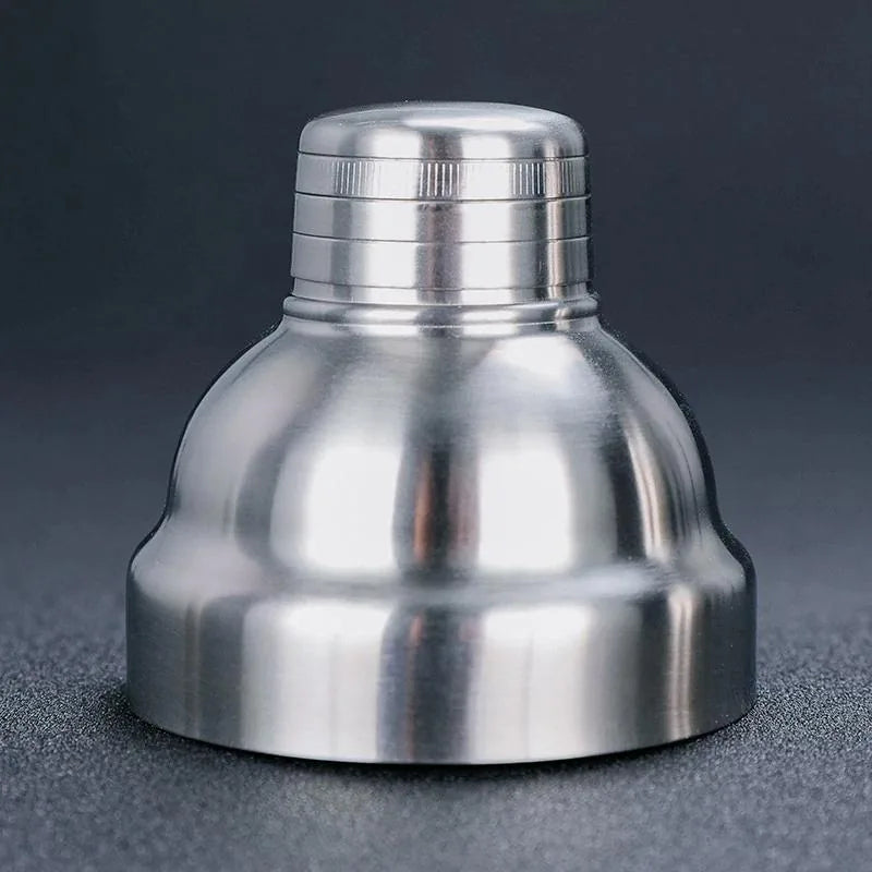 Gros plan sur le bouchon doseur strié du shaker cocktail classique en inox, posé seul sur fond sombre.
