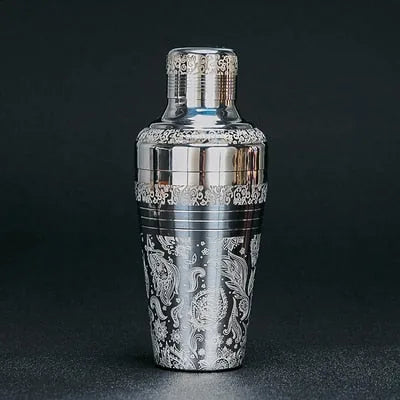 Shaker cocktail argenté gravé, mis en valeur sur fond sombre